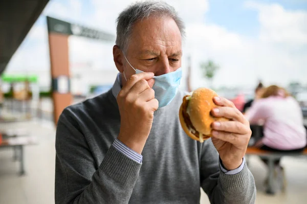 Зрелый Мужчина Пытающийся Съесть Гамбургер Маске Смешная Концепция Коронавируса — стоковое фото