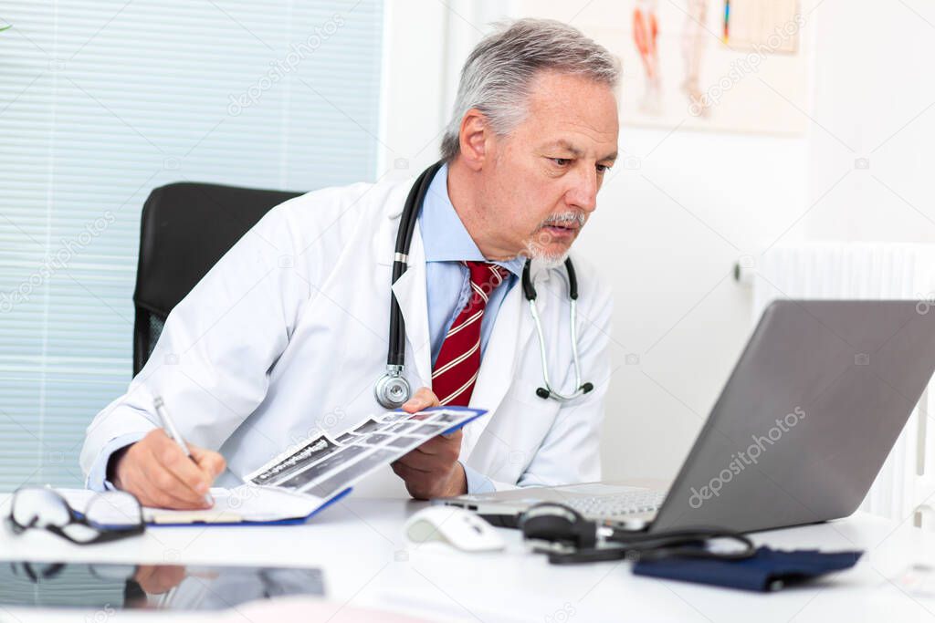 Senior doctor working at his laptop in his studio