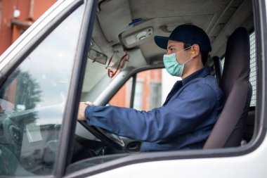 Koronavirüs salgını sırasında maskeli kamyon şoförü minibüs kullanıyor.
