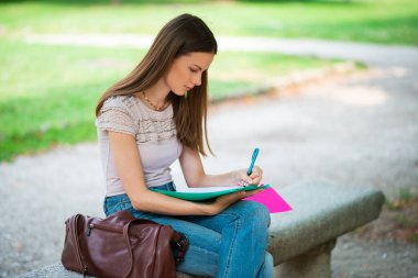 Young woman student studying outdoor in front of her school college, education and university concept