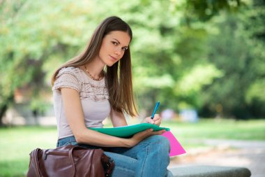 Young woman student studying outdoor in front of her school college, education and university concept