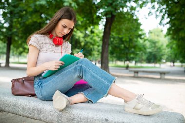 Young woman student studying outdoor in front of her school college, education and university concept