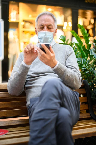 Hombre Mayor Sentado Banco Usando Teléfono Inteligente Centro Comercial Con — Foto de Stock