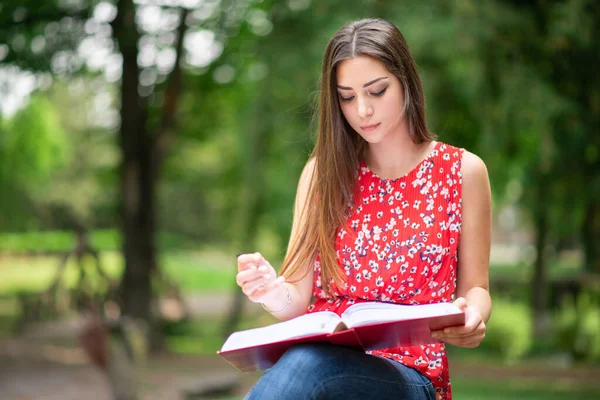 一个年轻的女学生在公园的室外写书 — 图库照片