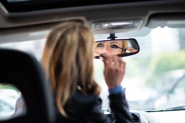 車の化粧を適用する女性 リアミラーからの眺め — ストック写真