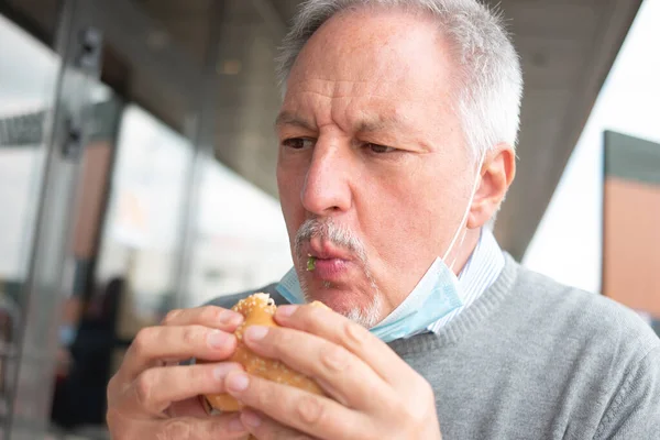 Hombre Comiendo Hamburguesa Comida Rápida Durante Con Una Máscara Barbilla — Foto de Stock