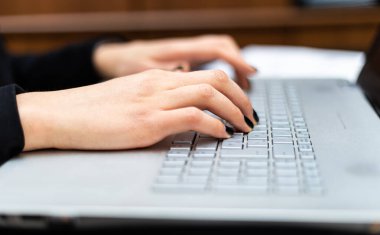 İş kadını iş yerinde dizüstü bilgisayarda yazıyor.