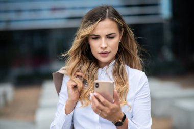 İş kadını ofisinin önünde cep telefonunu kullanıyor.