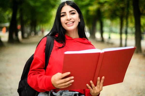 漂亮的女学生在户外拿着一本书 — 图库照片