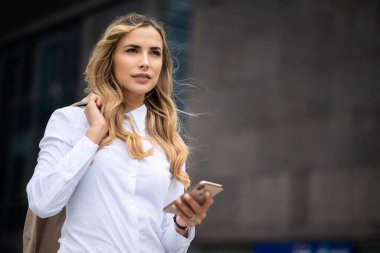 İş kadını ofisinin önünde cep telefonunu kullanıyor.