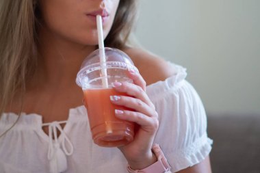 Evde greyfurt suyu içmek için pipet kullanan bir kadın.