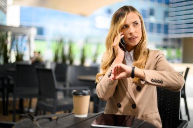 Molada telefonla konuşan ve saatini kontrol eden genç bir kadının portresi.