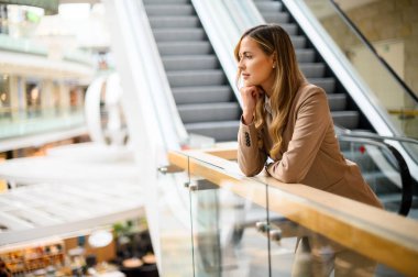 Düşünceli bir iş kadını. Düşünceli bir ifadeyle, parlak bir alışveriş merkezinde.