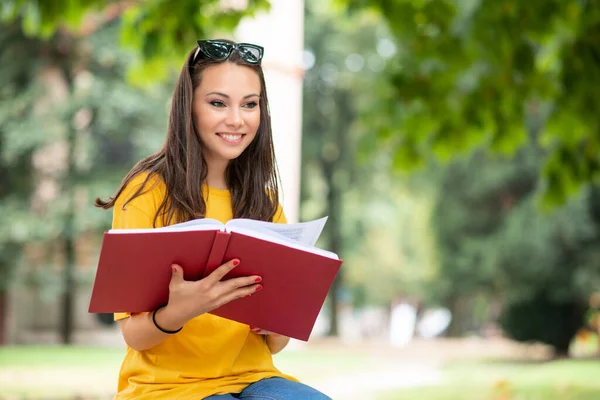 Kobieta Student Trzyma Książkę Przed Grupą Przyjaciół Parku — Zdjęcie stockowe