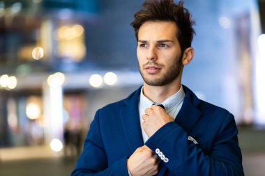 Genç işadamı akşam vakti dış görünüşünü düzeltiyor.