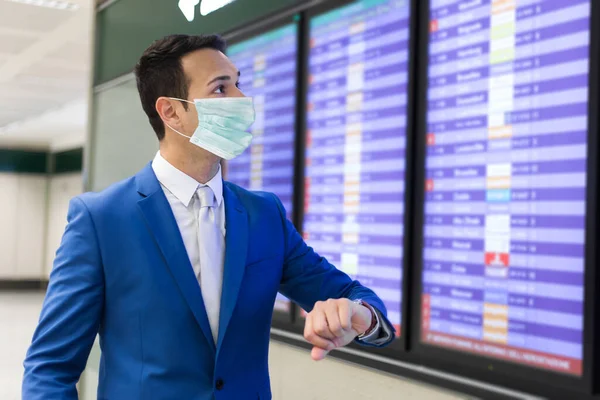 マスクを着用して空港で時間をチェックするビジネスマン コロナウイルスの概念 — ストック写真