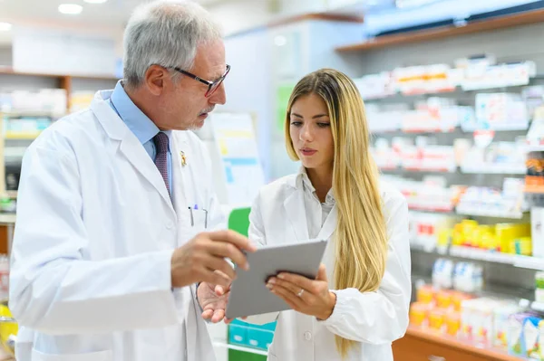 Dos Farmacéuticos Hablando Mientras Trabajan Tableta Tienda — Foto de Stock