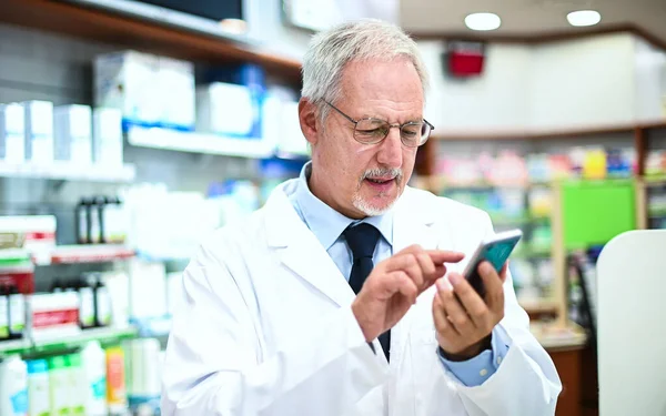 Apotheker Controleert Zijn Smartphone Tijdens Het Werken Zijn Winkel — Stockfoto