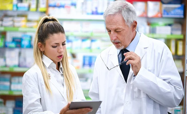 Twee Apothekers Praten Tijdens Het Werken Aan Tablet Hun Winkel — Stockfoto