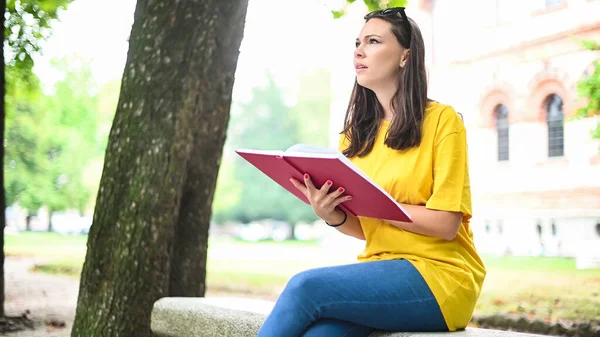 Güzel Bir Üniversite Öğrencisi Parkta Bir Bankta Kitap Okuyor — Stok fotoğraf