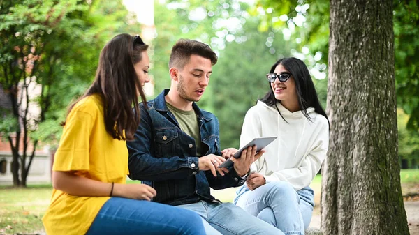 Tres Estudiantes Estudiando Juntos Con Una Tableta Digital Sentados Banco — Foto de Stock