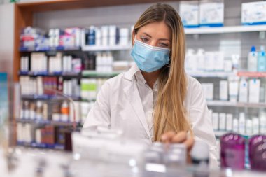 Genç bir kadın eczacı eczanenin envanterini kontrol ediyor.