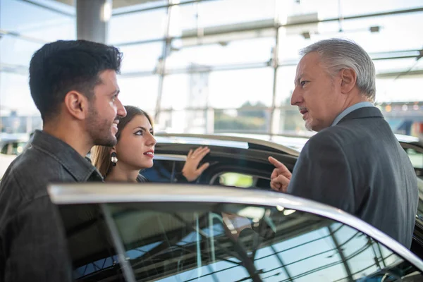 Feliz Jovem Família Conversando Com Vendedor Escolhendo Seu Novo Carro — Fotografia de Stock