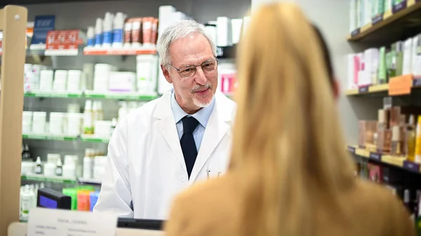 Senior pharmacist dealing with a customer