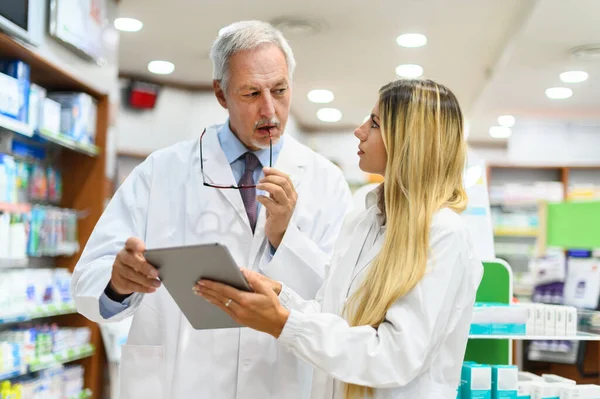 Dois Farmacêuticos Conversando Enquanto Trabalham Tablet Sua Loja — Fotografia de Stock