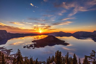 Glorious light as the sun is rising at Crater Lake National Park, Oregon. Perfect reflection and silhouette of wizard island clipart