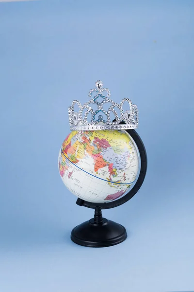 plastic globe with crown on blue background