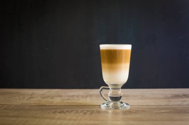 Siyah arka planda bir bardak macciato latte. Kakaolu sütlü köpüklü kapuçino. Seçici odak, boşluğu kopyala