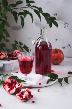 Cam şişede beyaz tepside yeşil yapraklı nar suyu. Organik, sağlıklı, ev yapımı içki konsepti. Boşluğu kopyala