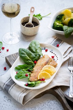 Tilapia balığı kızartılmış ve taze ıspanak yaprakları ve beyaz şarapla servis edilen limon dilimleri ile servis edilmiş. Donmuş balık parçaları ile sağlıklı ev yapımı gıda konsepti. Boşluğu kopyala