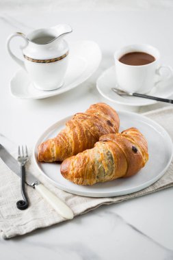 Kahveyle kahvaltı, beyaz fincanda kruvasan ve mermer arka planda tabak. Sağlıklı ev yapımı hamur işi, kopyalama alanı