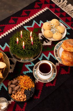 Novruz Green buğday çimeni semeni veya sabzi, Azerbaycan, İran 'ın yeni yılı. Ahşap kahverengi arka planda doğu motifleri desenli halı. Ulusal halı ve yiyecek. 