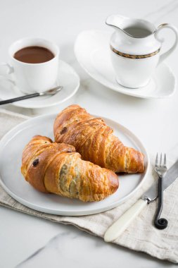 Kahveyle kahvaltı, beyaz fincanda kruvasan ve mermer arka planda tabak. Sağlıklı ev yapımı hamur işi, kopyalama alanı