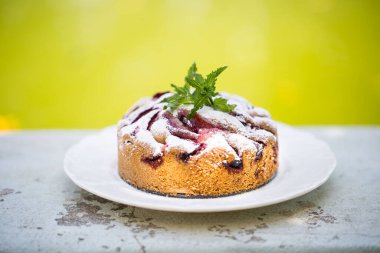 Şeker tozlu erikli kek beyaz tabakta  