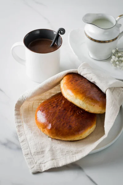 Breakfast with coffee and bun in white cup and plate on marble background. Healthy homemade pastry, copy space