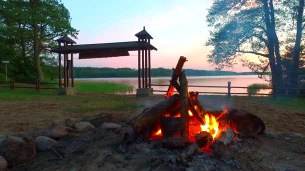 Vreugdevuur bij zonsondergang aan het meer in de zomer — Stockvideo