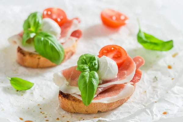 Bruschetta Med Lufttorkad Skinka Tomat Och Mozzarella Vitt Bord — Stockfoto