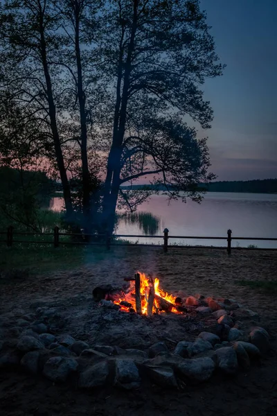 Warm bonfire at dusk by the lake in summer