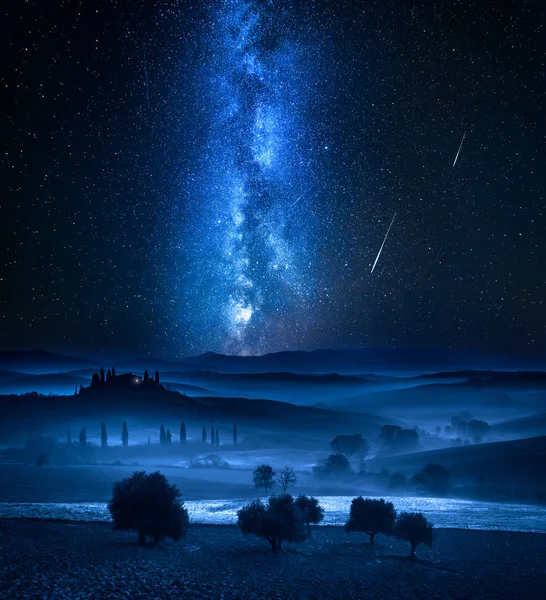 Milky way and falling stars over valley in Tuscany, Italy