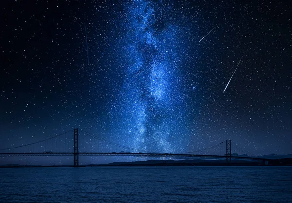 Milky way and falling stars over bay in Queensferry, Scotland