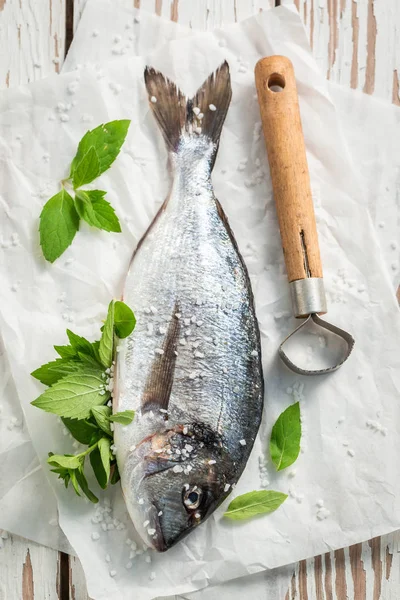 Würzen von frisch gefangenem Fisch mit Salz auf weißem Tisch — Stockfoto