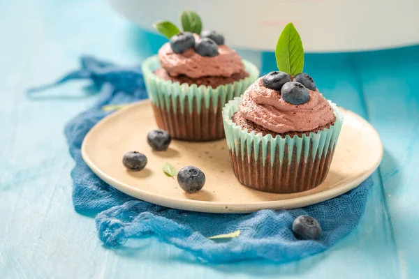 Muffin with blueberries and chocolate cream on blue table — Stock Photo, Image