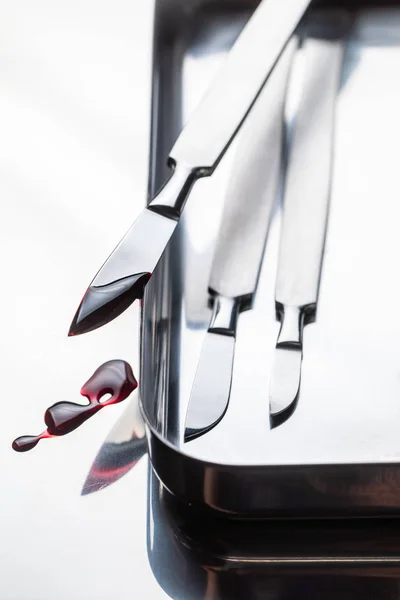 Closeup of scalpels on stainless steel table with blood — Stock Photo, Image