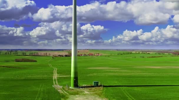 Біла вітрова турбіна на зеленому полі навесні, вид з повітря — стокове відео