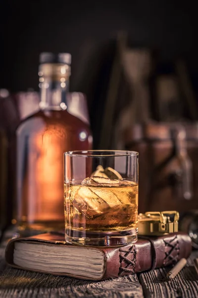 Gros plan de verre de whisky avec glace et bouteille dorée — Photo