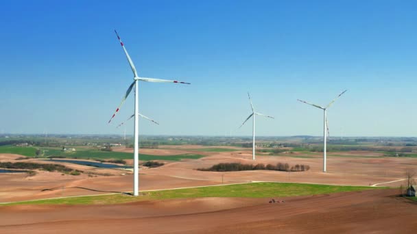 Большие ветроэлектростанции в поле с небольшим трактором для вспашки — стоковое видео